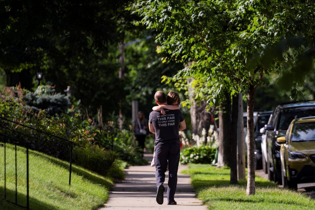 A father carries his daughter as they walk toward their vehicle after a shooting at Annunciation Church, which is also home to an elementary school, in Minneapolis, Minnesota, on Aug. 27, 2025.
